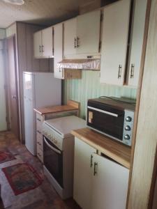 a small kitchen with white cabinets and a black microwave at Mobil-home in Rebaïb