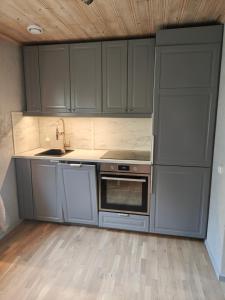 a kitchen with gray cabinets and a stove top oven at Muminhuset i Norberg in Norberg +19 photos