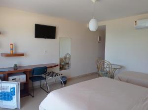 a bedroom with a bed and a desk and a tv at Pousada Canto da Baleia in Arraial do Cabo
