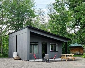a small black house with chairs and a picnic table at Camping Abenaki Aventure - Les Chalets in Pierreville