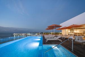 a swimming pool with lounge chairs and umbrellas at Hotel Casa Bahía Cozumel - Adults Only in Cozumel