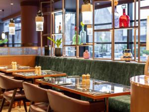 a restaurant with wooden tables and chairs and windows at TRIBE Hotel Den Haag Centraal - Opened December 2025 in The Hague