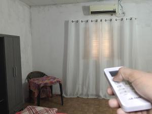 a person holding a remote control in front of a window at Pousada Mais E Vida 24h in Teresina