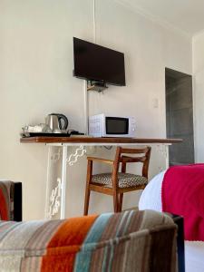 a room with a desk with a microwave and a tv at Lapaleholo Guesthouse in Phuthaditjhaba