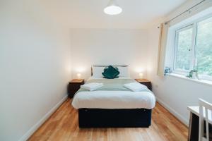 a bedroom with a bed with two night stands and two windows at The Coastal Breeze in Porthmadog