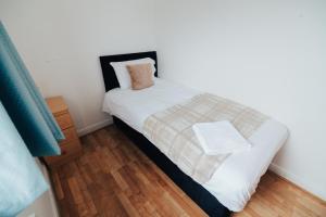 a small bedroom with a bed and a wooden floor at The Coastal Breeze in Porthmadog +9 photos