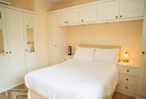 a bedroom with a white bed and white cabinets at Ger Y Llanw Aberaeron in Aberaeron