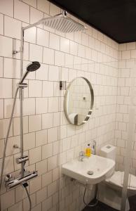 a white tiled bathroom with a sink and a mirror at Autokeidas Forssa Motelli in Forssa