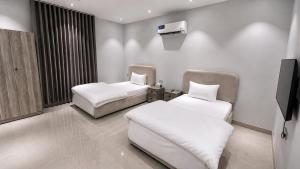 a room with two beds and a flat screen tv at أرياف سويت in Al Baha