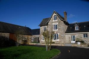 a large stone house with a black roof at Gîte La Ferme Ecole in Perrou