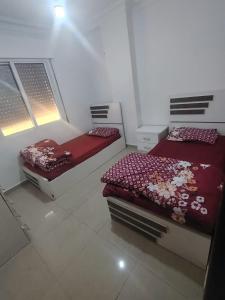 ein Schlafzimmer mit zwei Betten und zwei Fenstern in der Unterkunft Remas23 in Irbid