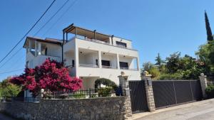 a white house with a fence and pink flowers at Apartmani Nika in Rijeka