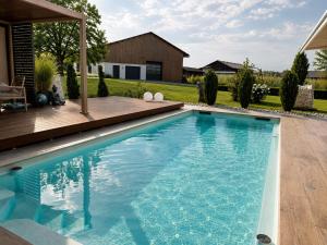a swimming pool in a backyard with a wooden deck at KOASA HOF Bed and Breakfast in Oberhaag