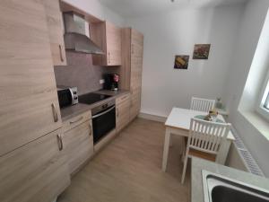 a kitchen with wooden cabinets and a table with a chair at Appartement Weideblick in Steinsieken