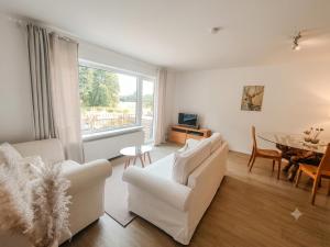 a living room with white furniture and a table at Appartement Weideblick in Steinsieken