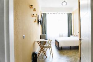a bedroom with a bed and a desk and a window at Gazulli Guesthouse in Lezhë