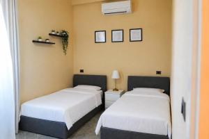 two beds in a room with white sheets at Gazulli Guesthouse in Lezhë