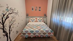a small bedroom with a bed and a tree on the wall at Dimora Clorinda in Passo Corese
