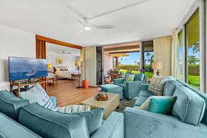 a living room with blue couches and a television at Maui Eldorado Condo J123 in Kaanapali