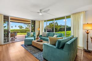a living room with blue furniture and large windows at Maui Eldorado Condo J123 in Kaanapali