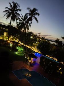 a view of a pool at night with palm trees at Rancho do Mirante in Araçatuba