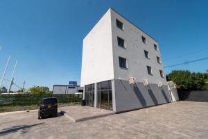 a white building with a car parked in front of it at NORTH GATE Rooms in Afumaţi