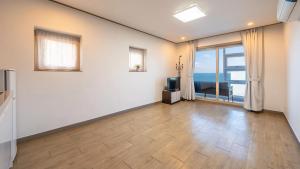an empty living room with a television and a large window at Samcheok jangho sanho Pension in Samcheok