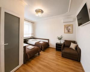 a room with two beds and a couch and a chair at Family ЛюКс in Kamianets-Podilskyi