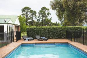 a pool with two lounge chairs next to a fence at Eurunderee House in Eurunderee