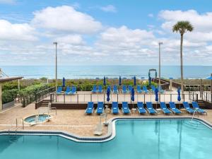 a swimming pool with blue chairs and the ocean at DoubleTree Suites by Hilton Melbourne Beach Oceanfront in Melbourne