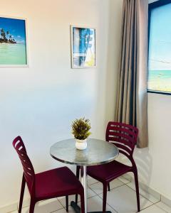 a table with two chairs and a vase on it at Maraga Beach Hostel in Maragogi