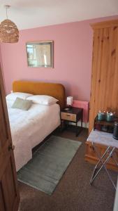 a bedroom with a bed with pink walls at Lodge hill cottage in Liskeard