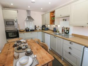 a kitchen with white cabinets and a wooden table at Banklands in Barnard Castle