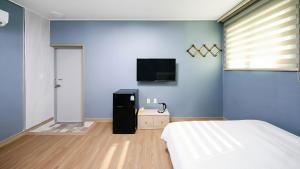 a bedroom with a bed and a tv on a blue wall at Yeosu Trip Pension in Yeosu