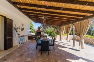 a patio with a table and chairs under a wooden pergola at Casina dei Capperi by Vivimy in Torre Pali