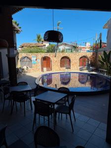 a patio with tables and chairs and a swimming pool at Pousada Ocean Mare in Praia do Frances