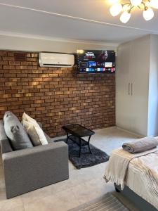 a living room with a couch and a tv on a brick wall at Whale's Cove in Amanzimtoti