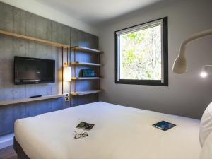 a bedroom with a bed and a tv and a window at Ibis Budget Château-Thierry in Essômes-sur-Marne +81 photos