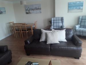 a living room with a black leather couch and chairs at isleofmanholidayapartment in Douglas