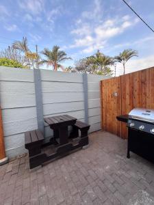 a picnic table and a grill next to a fence at Whale's Cove in Amanzimtoti