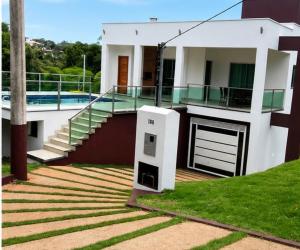a white house with a staircase and a balcony at Paraíso Escarpas do Lago 1 - Capitólio in Capitólio