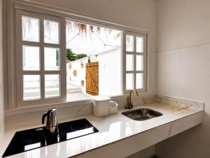 a kitchen with a sink and two windows at Raya Beach Studios in Maresias