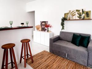 a living room with a couch and two stools at Raya Beach Studios in Maresias