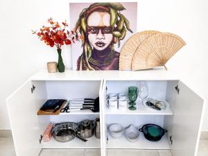a white cabinet with a painting of a man at Raya Beach Studios in Maresias +28 photos
