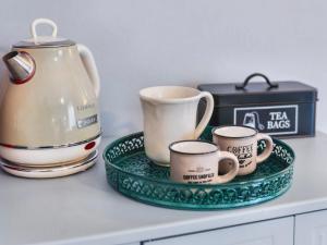 a tray with three coffee cups and a tea bag at My Tuscany Turquoise Suite in San Quirico dʼOrcia +9 photos