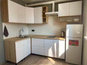 a kitchen with white cabinets and a refrigerator at Mini home apartment in Ternopil