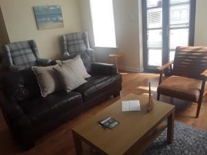 a living room with a black couch and a coffee table at isleofmanholidayapartment in Douglas
