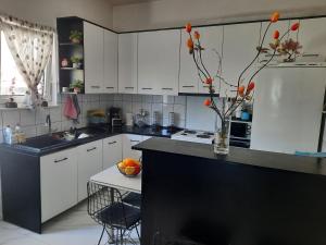 a kitchen with white cabinets and a vase of flowers on the counter at Tania's house in Tríkala