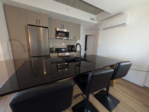 a kitchen with a black counter top and black chairs at Suites Cobalt in Quebec City