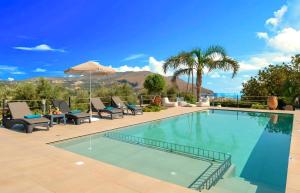 a swimming pool with chairs and an umbrella at Cretan Dream Villa in Georgioupolis